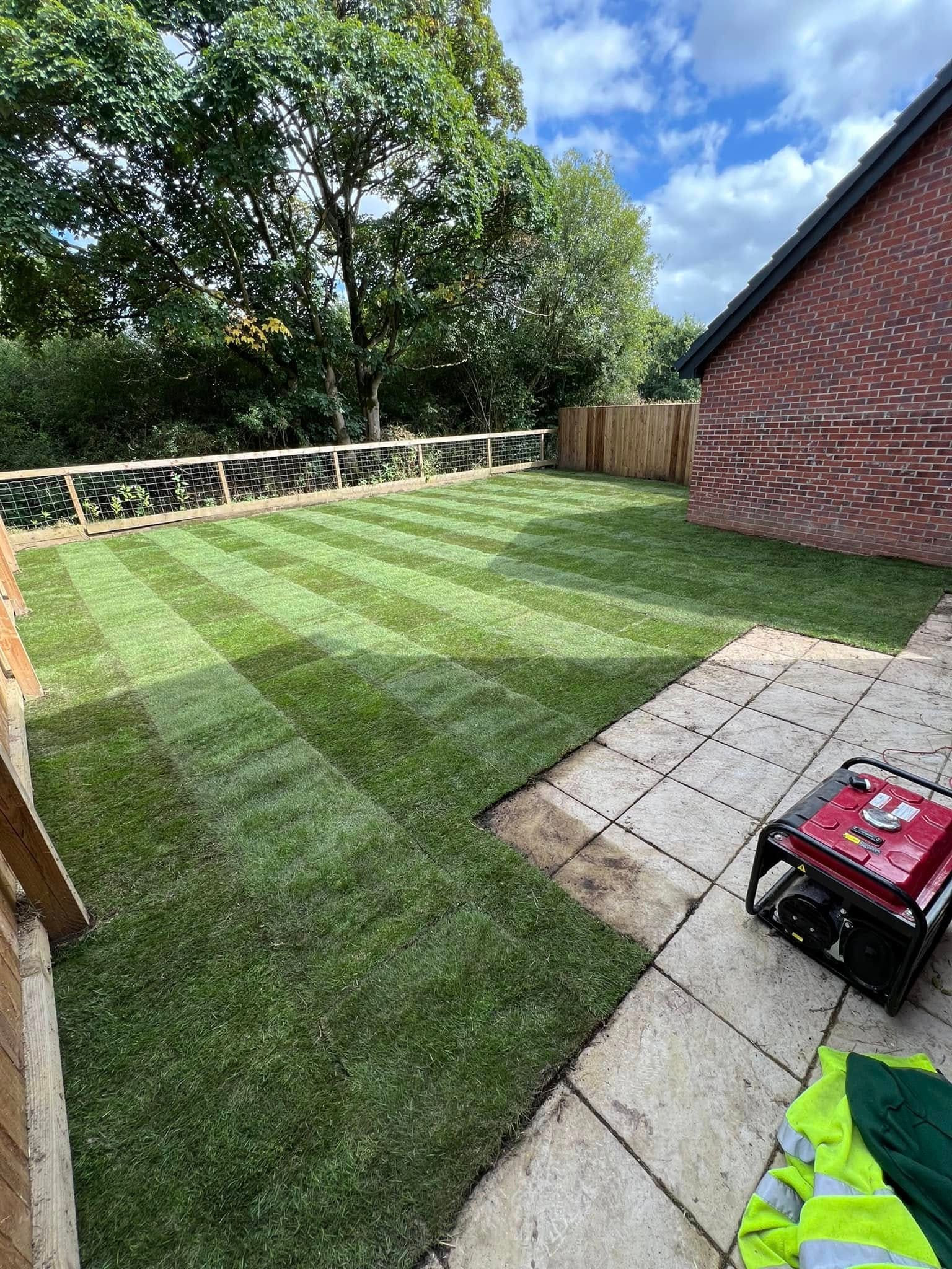 After: turfed garden with patio seating area and brick wall border